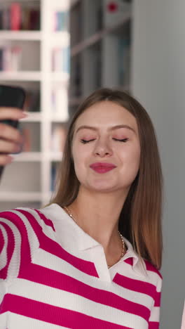 women take selfie against bookshelves. pretty students girl friends take photo for social media finishing project in library. young bloggers in bookstore