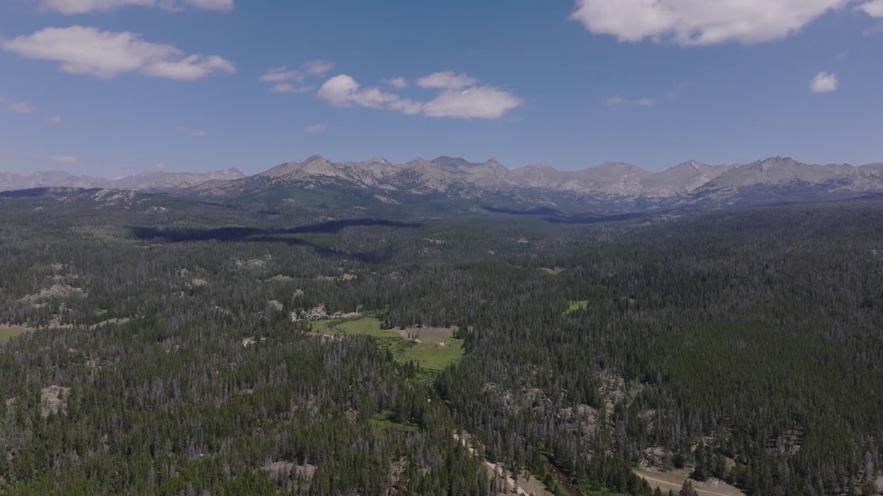 establecimiento panorámico aéreo del desierto de wind river, wyoming, capturando picos de montañas, bosques verdes y llanuras expansivas cerca del gran comienzo de sendero de arena