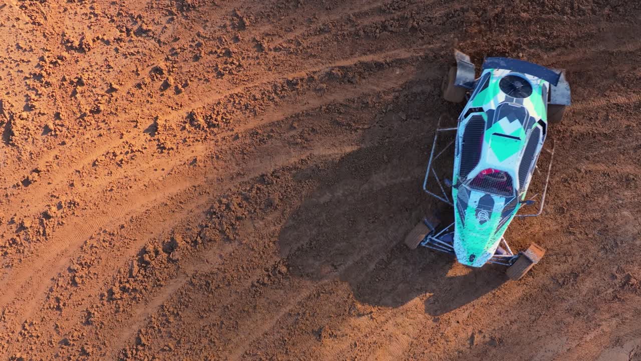 Vista aerea di un buggy da corsa fuoristrada che corre e affronta una curva su pista sterrata al rallentatore. Ripresa dall'alto.