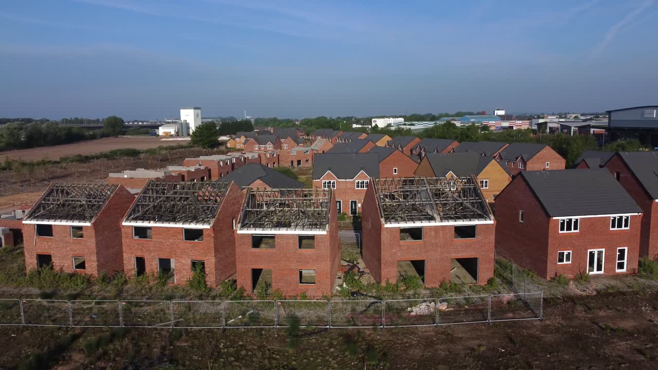 Residential housing framework aerial view wide orbit across unfinished rooftop development on urban building site real estate