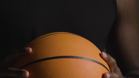 close up studio shot of male basketball player with hands holding ball