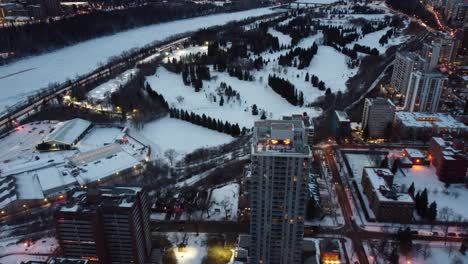 2-2aerial birds eye view flydown night time over winter futuristic modern residential rivers edge high rises by golf course indoor tennis club cross country skiing snow shoeing posh upscale university