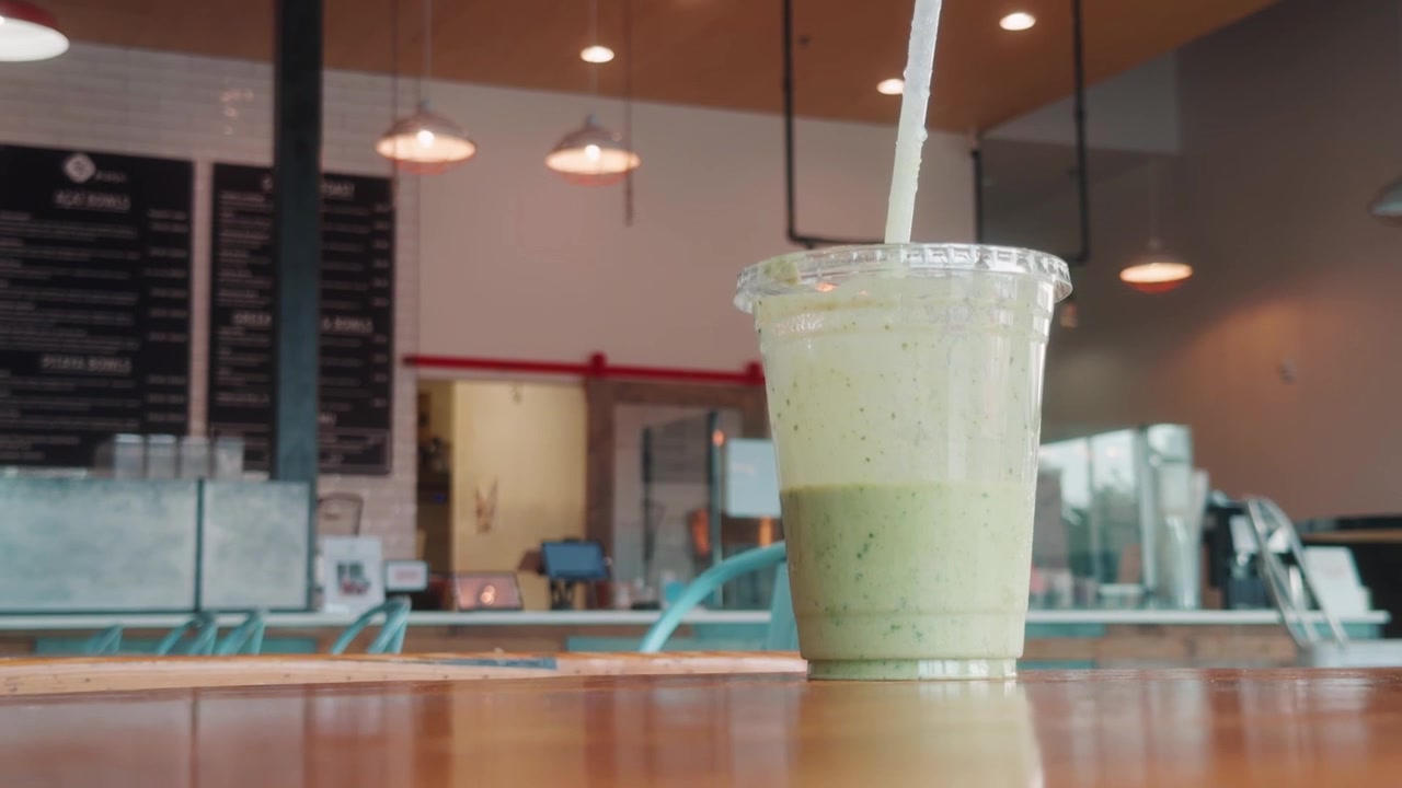 Camera glides downward as a green smoothie disappears behind a table.