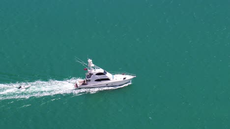 Beautiful-tracking-shot-of-Yacht-in-turquoise-blue-seas-from-top-of-Dukes-Nose-Track,-Totara-North,-Northland,-New-Zealand