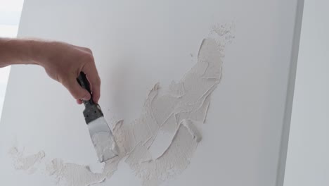 person applying plaster to a wall with a putty knife