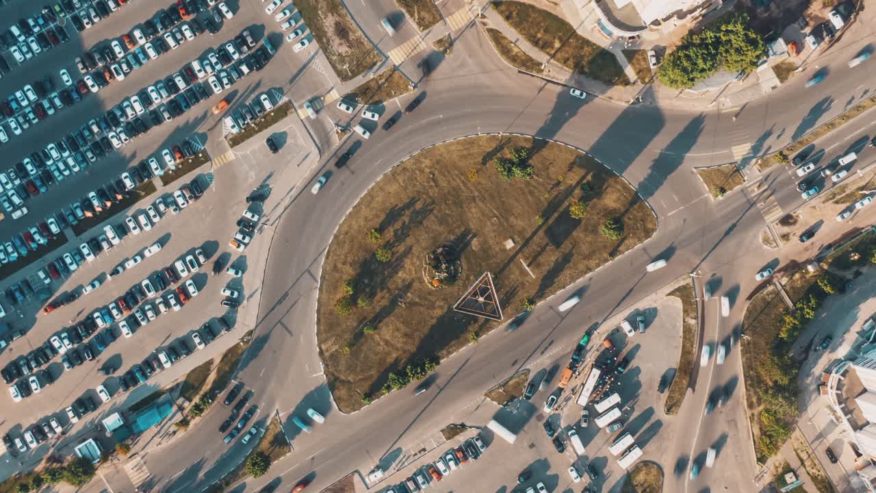 vista aérea de una intersección de la ciudad ocupada con estacionamientos y una rotonda