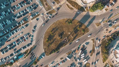 vista aérea de una intersección de la ciudad ocupada con estacionamientos y una rotonda
