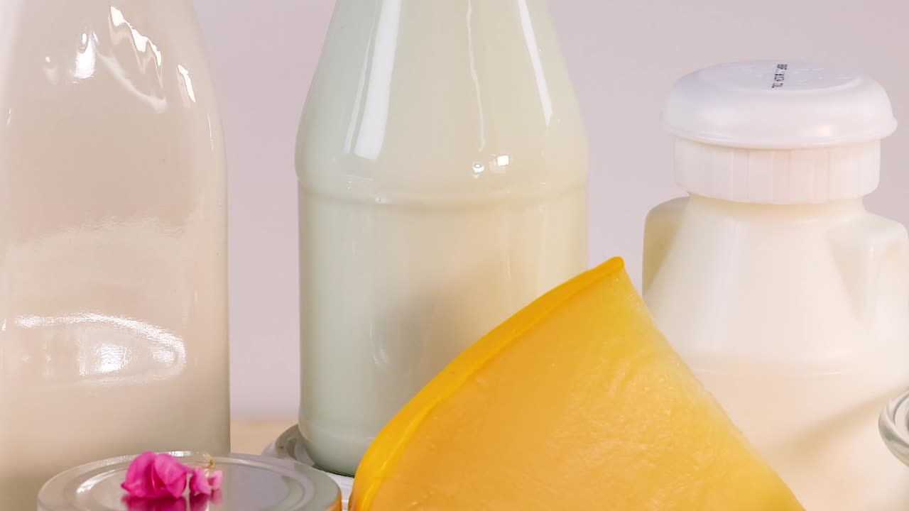 An assortment of cheeses and milk bottles arranged neatly with a touch of herbs and flowers.