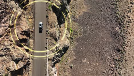 top down aerial shot of a self driving car making its way through a steep desert cliff roadway