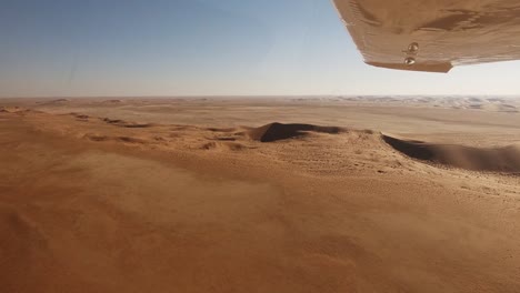 mirando bajo el ala a través de las interminables dunas del desierto de namib