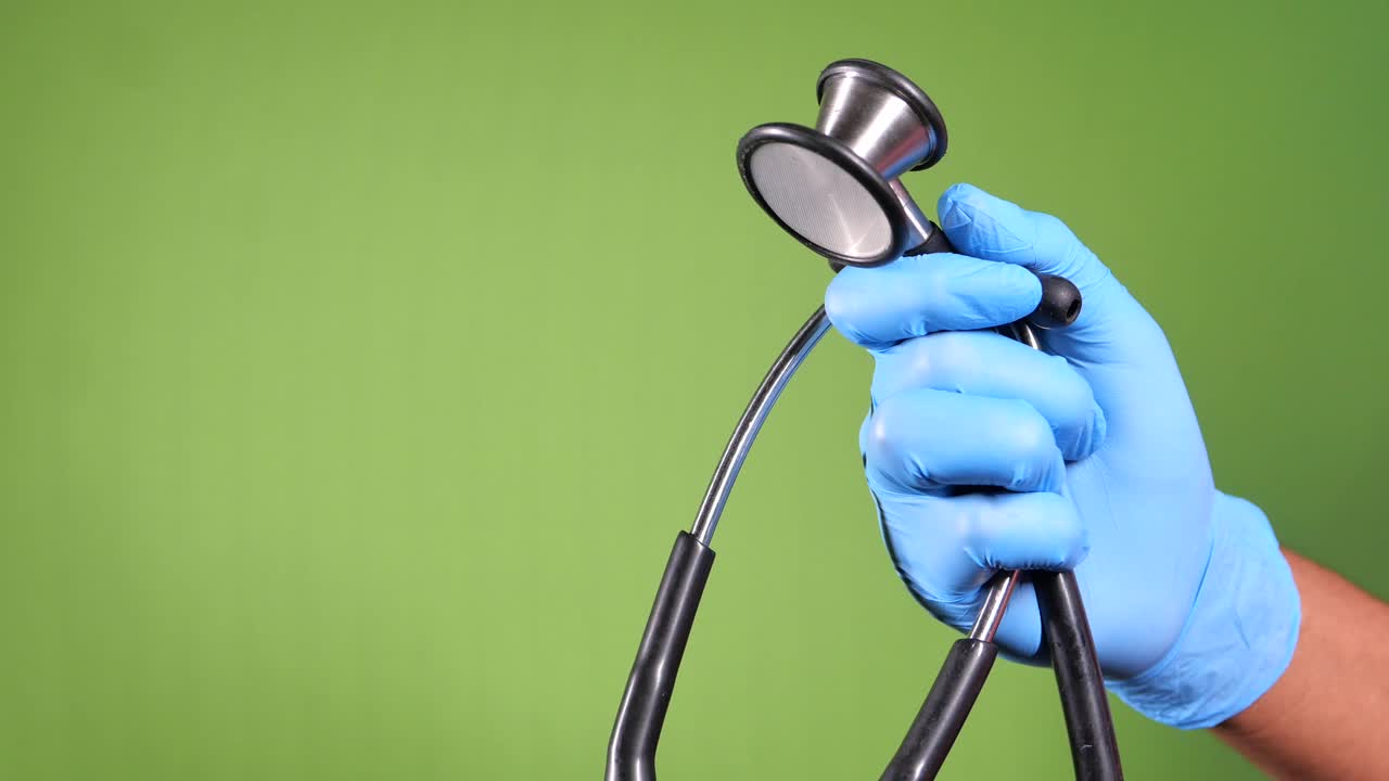 Nahaufnahme einer Hand in einem blauen Handschuh, die ein Stethoskop hält