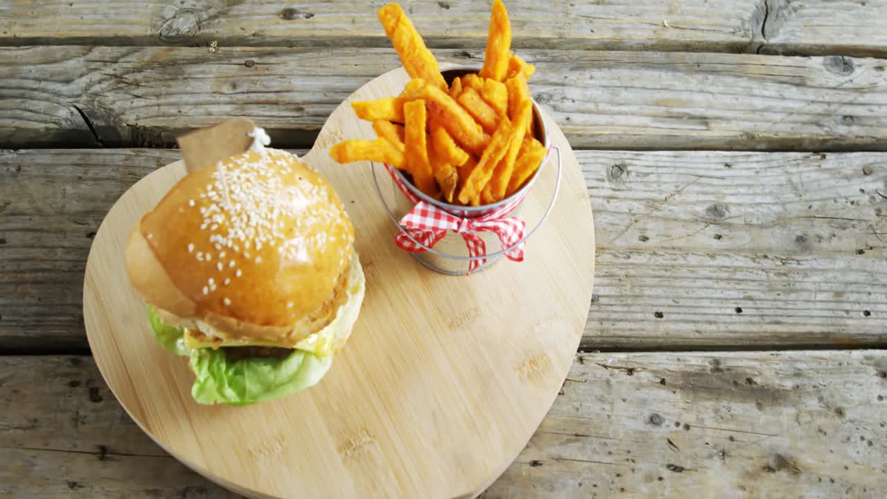 hamburguesa francesa con papas fritas en el cubo mantenido en la mesa
