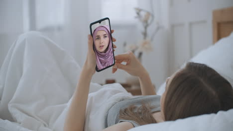 Mujer-Usando-Una-Aplicación-Médica-En-Un-Teléfono-Inteligente-Consultando-Con-Una-Mujer-árabe-Musulmana-Con-Un-Médico-Hijab-A-Través-De-Videoconferencia.-Mujer-Que-Usa-Chat-En-Línea-Para-Hablar-Con-Un-Terapeuta-Familiar-Y-Una-Pandemia-De-Coronavirus.