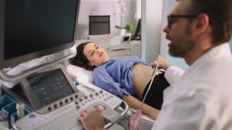 doctor performing ultrasound on a female patient's abdomen