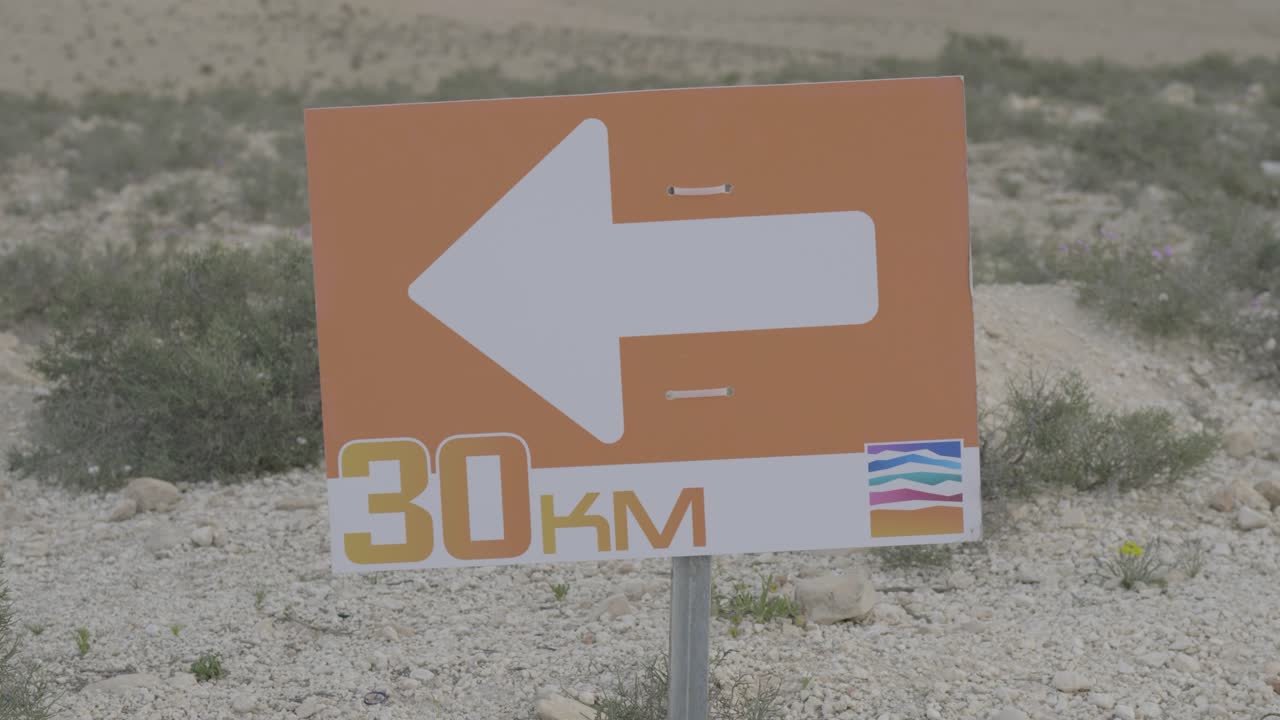 Close up of directional orange sign on race trail indicating turn during outdoor event, 30km mark