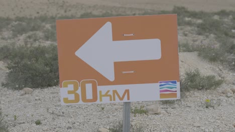 close up of directional orange sign on race trail indicating turn during outdoor event, 30km mark
