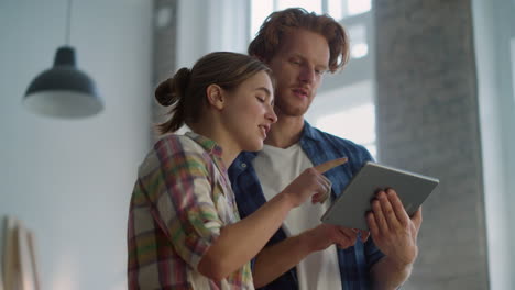 happy couple using tablet for home repair. family looking pictures online.