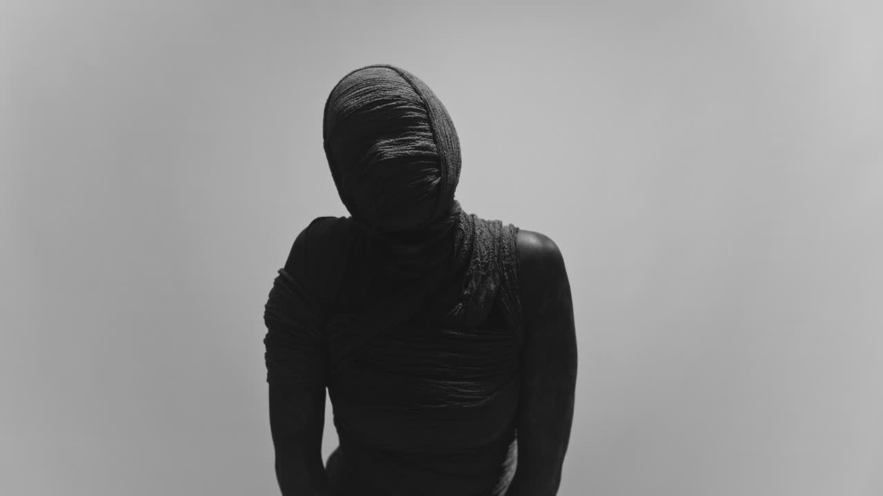 A mummy of a woman on a white backdrop moves her head