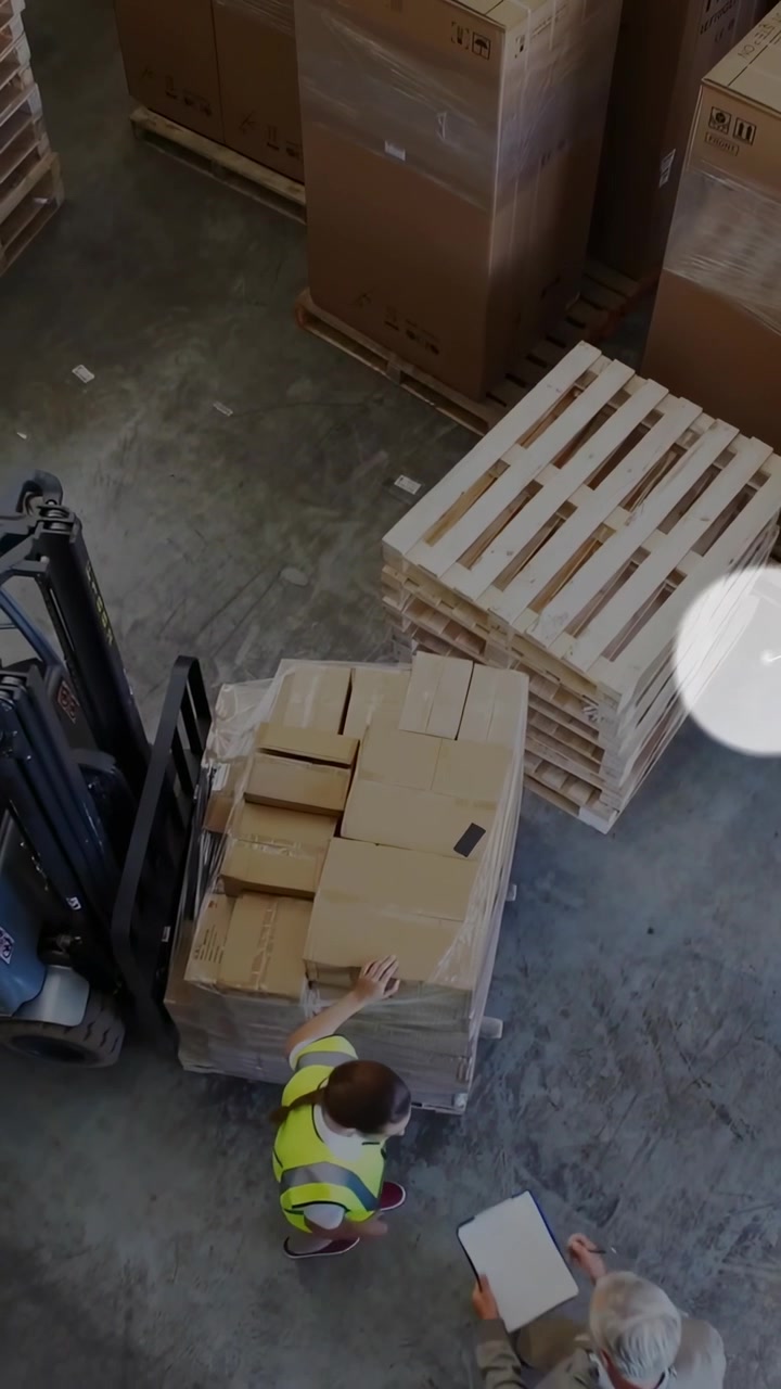 Video vertical: Personal del almacén golpeando el palé mientras el gerente muestra documentos, revisando la carga, indicadores subiendo