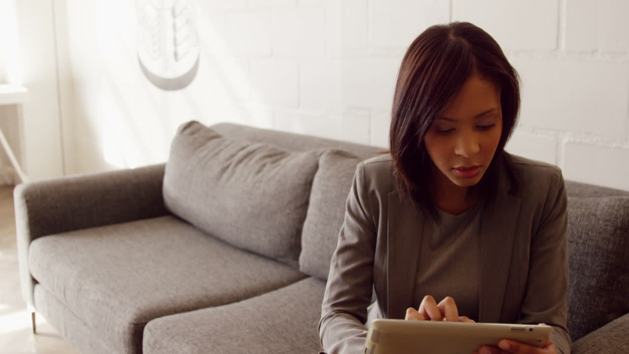 Smiling businesswoman using her tablet on the couch