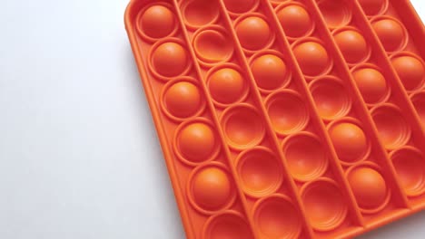 new baby toy. pop it finger play. funny color. colorful game spin on white table. orange square
