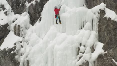 climber climbs frozen ice sheet cascade with axes aerial 4k