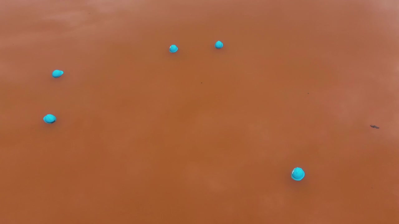 A drone flies forward over the reddish muddy waters of Lac Rose near Dakar, Senegal.