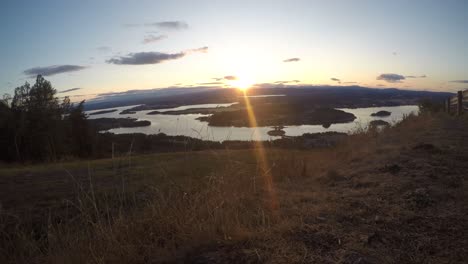 sunset in alpen mountains displays its beauty to the peaceful lake surrounded by trees and grass - golden hour - wide shot