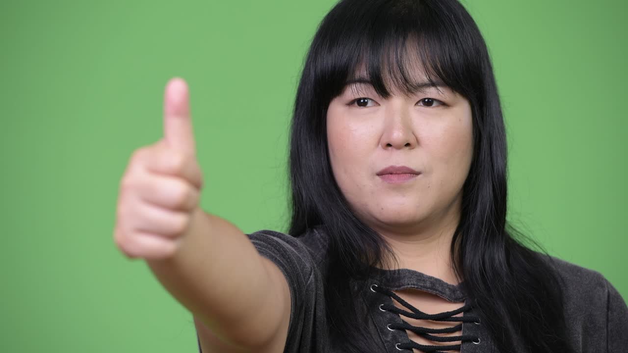 Happy overweight Asian woman giving thumbs up