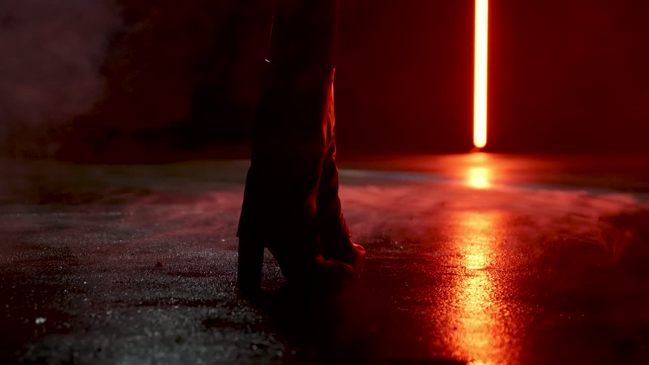 mujer de pie con botas en la calle húmeda y con niebla en cámara lenta