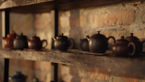 a collection of brown teapots on a wooden shelf