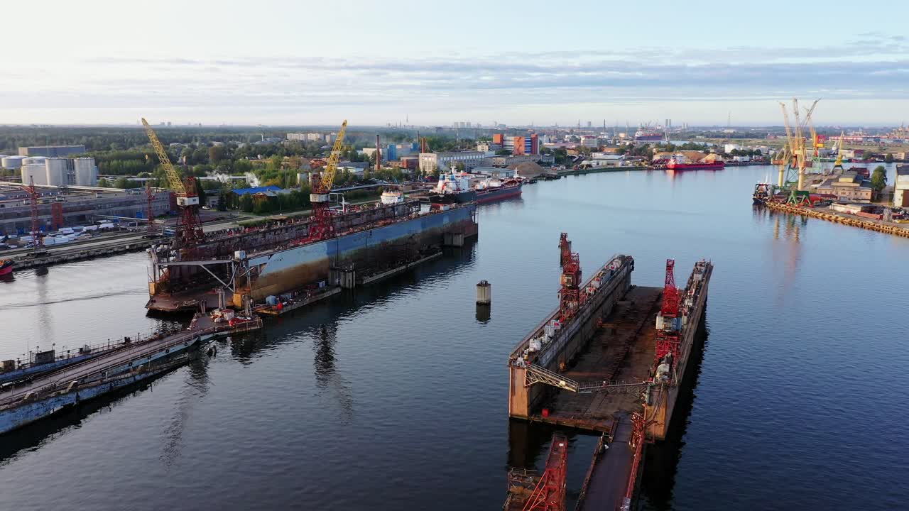 Aerial footage of Riga shipyard dry docks and cranes lining the harbor edge