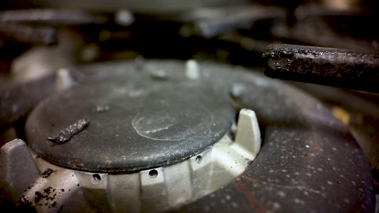 Close-up view of a gas stove burner with soiled control knob, kitchen detail and texture