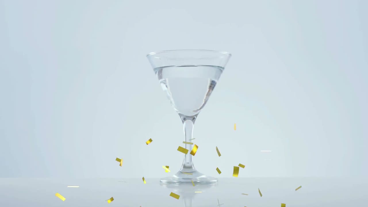 골든 콘페티가 올리브 위로 떨어지고 회색 배경에  ⁇ 테일 잔으로 떨어집니다.