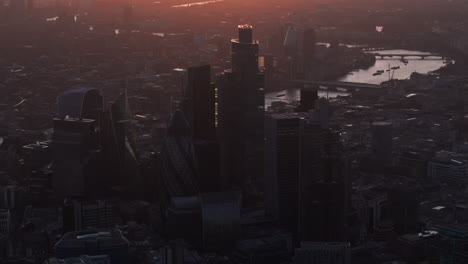 dark circling aerial shot of the city of london skyscrapers at sunset