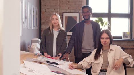 multiethnic team of young graphic designers looking and smiling at camera in an animation studio