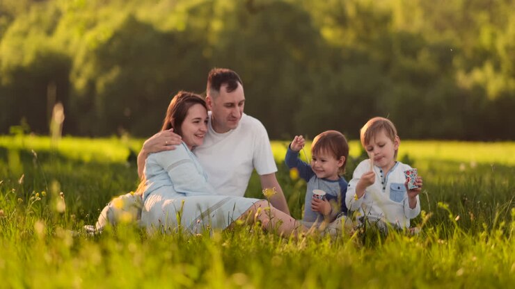 una famiglia felice in un picnic in estate si divertono a parlare ridendo e mangiando gelato al rallentatore.