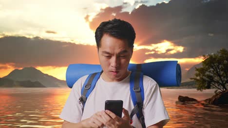 close up of asian male hiker with mountaineering backpack looking at the smartphone and saying wow at a lake