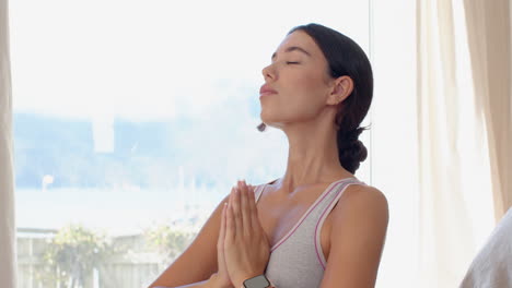 young woman meditating at home, eyes closed, feeling peaceful and relaxed