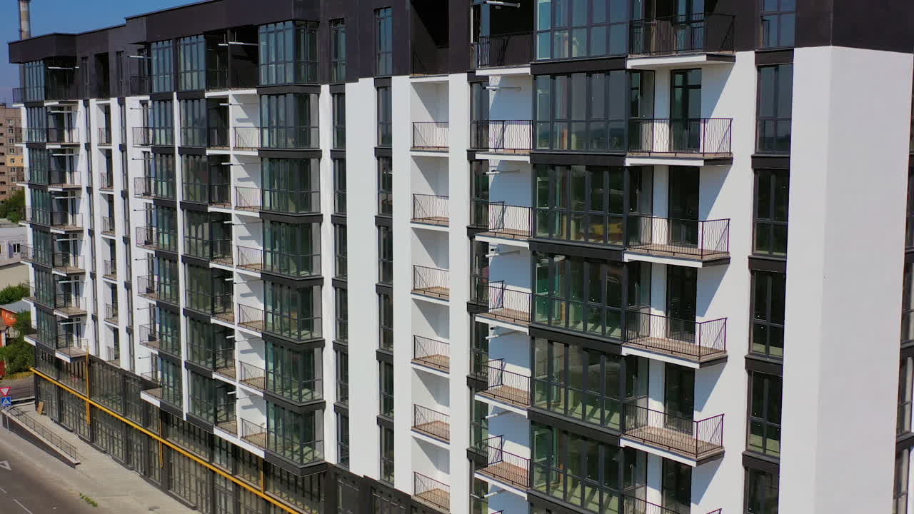 New architecture in the city. Luxury design of apartment building in a sunny day. Black and white high-rise apartment with balconies.