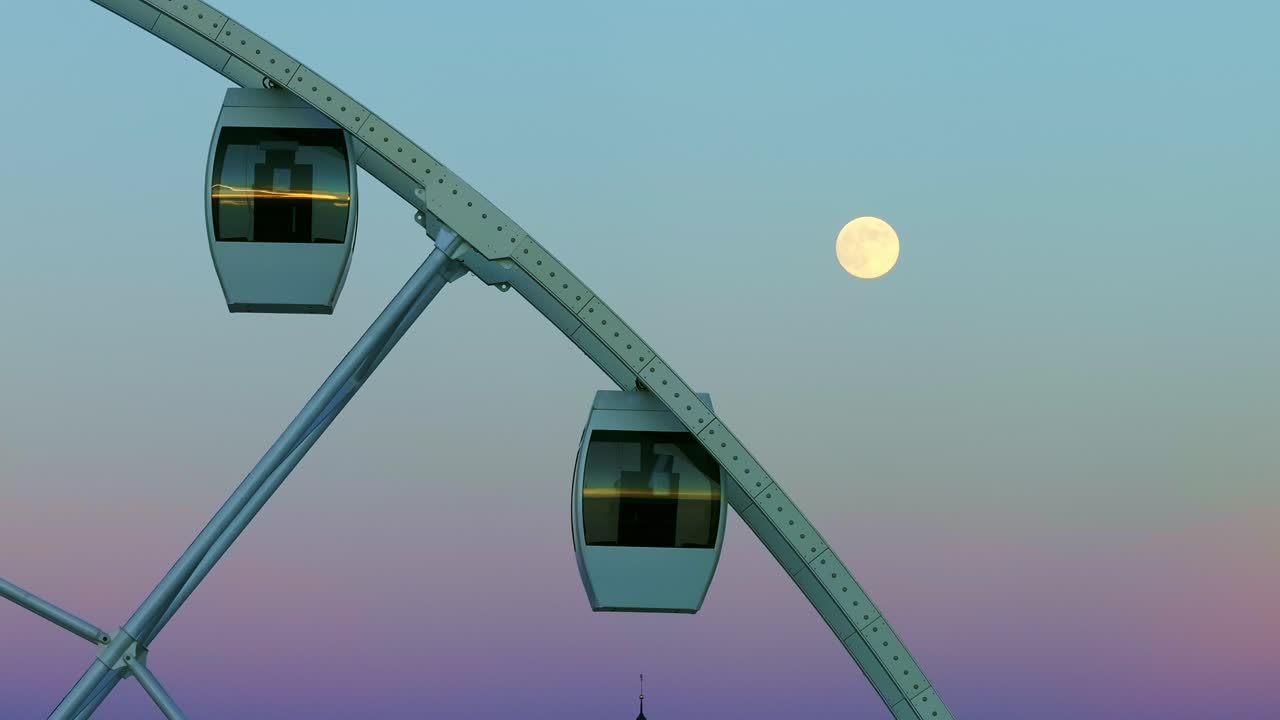 Close-up of Ferris wheel with full moon, pastel twilight sky creating calm scene