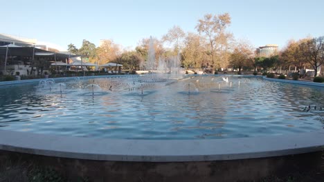 Piscina-Con-Fuente-Que-Decora-El-Parque-Central-Rinia-En-Tirana,-Albania---Amplia-Toma-De-Seguimiento-De-Diapositivas