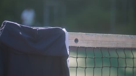 Close-up-of-a-Tennis-net,-Man-and-Woman-Leave-a-Tennis-Court