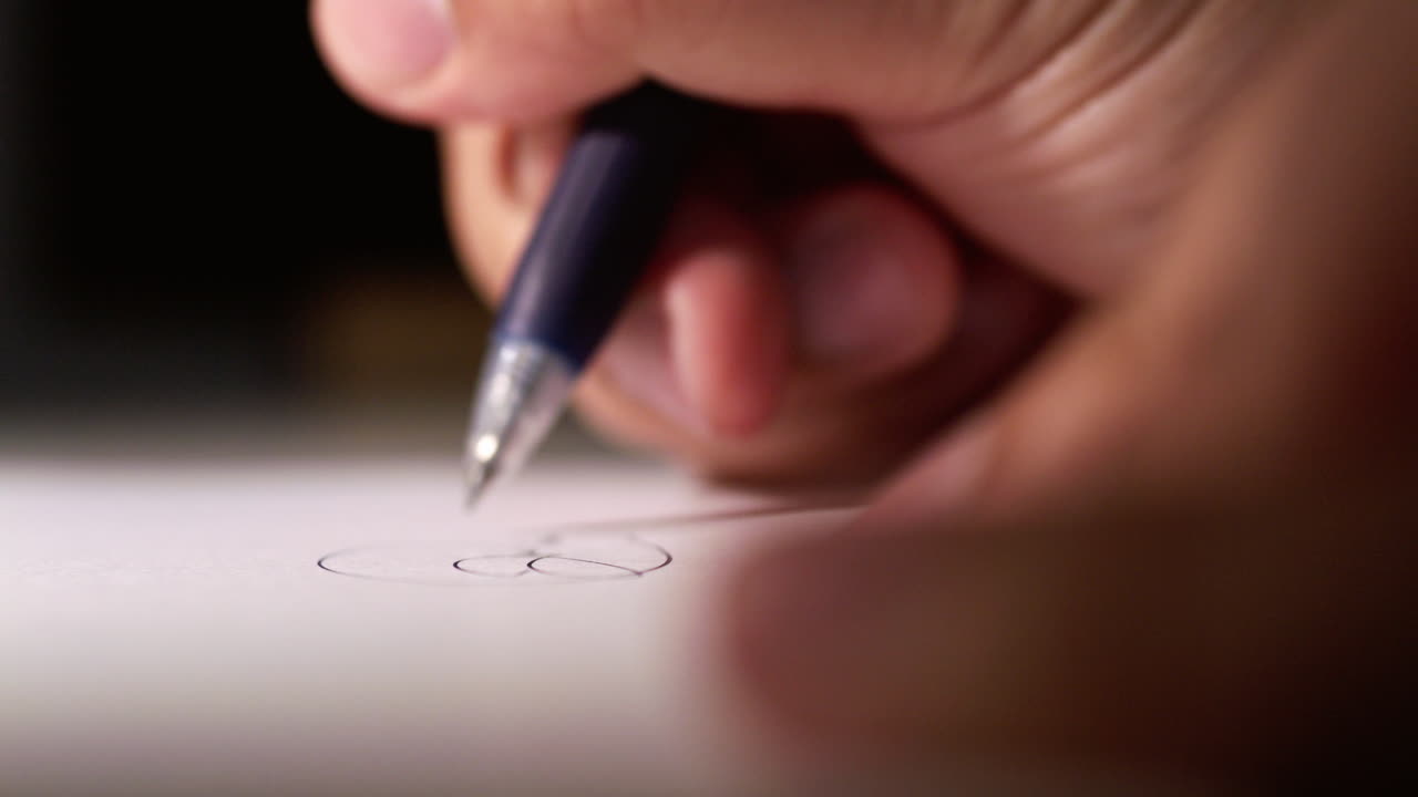 Close-up of a hand drawing with a pen on paper