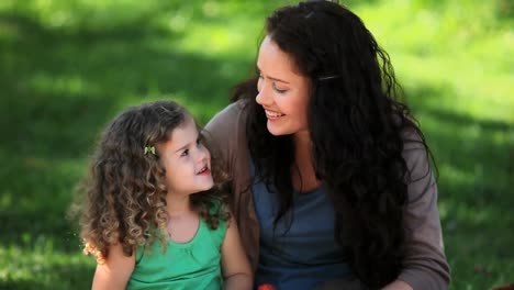 Mother-and-daughter-enjoying-strawberries-sitting-on-the-grass