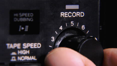 adjusting the recording volume knob on a vintage stereo tape recorder