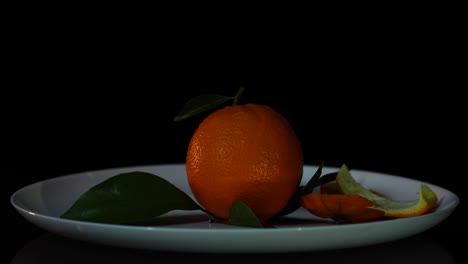 orange with leaves and peels falling into plate, fresh juicy citrus for fruit salad