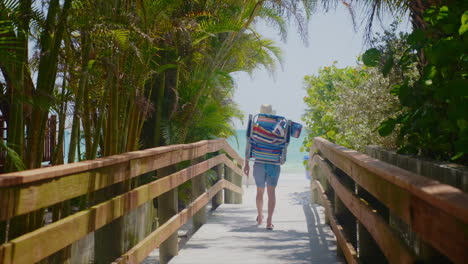 beach bum walks down pathway towards florida beach and ocean