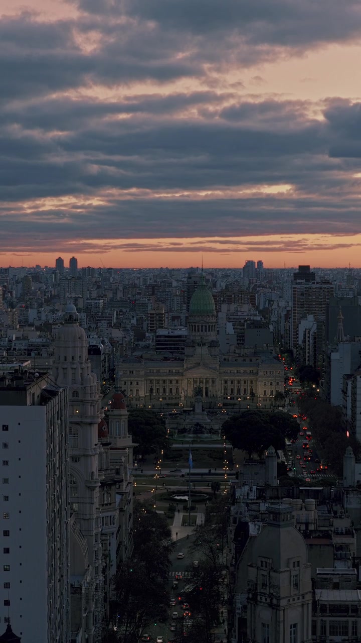 Panoramica aerea verticale verso sinistra sul Congresso Nazionale Argentino, sui viali circostanti e sullo skyline della città al tramonto a Buenos Aires