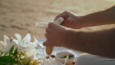 man hands relaxing picnic on summer beach closeup. unknown guy breaking bread